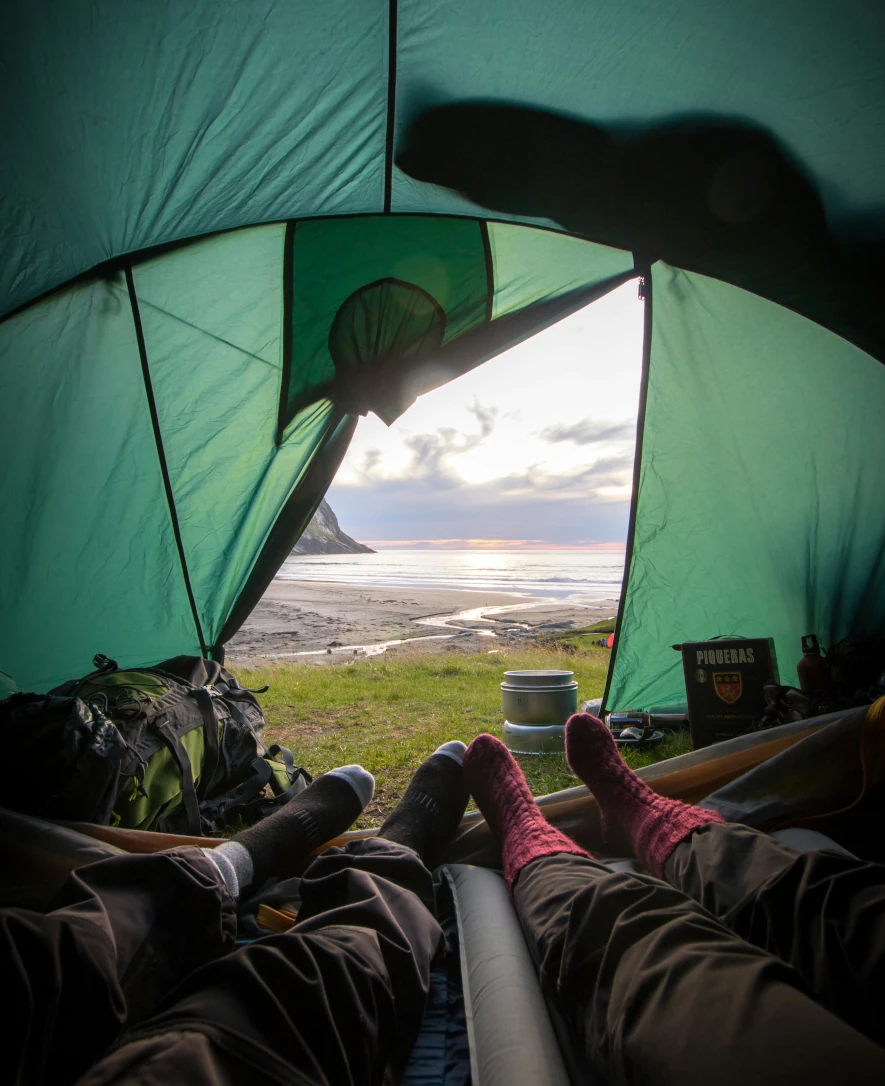 telt like ved strandkanten i Lofoten, fotografert innenfra teltet med føttene våre i teltåpningen