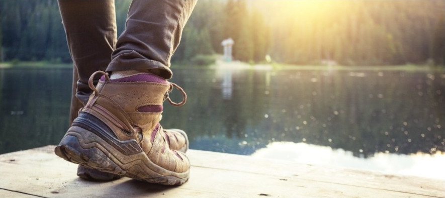 Står med sko på en brygge ved vann i skogen